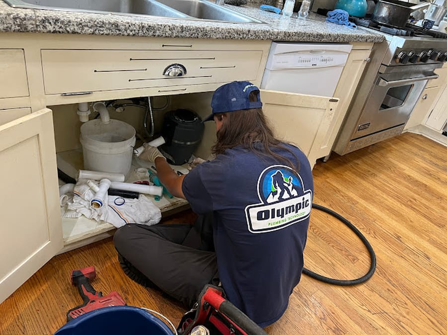Man underneath sink drain descaling