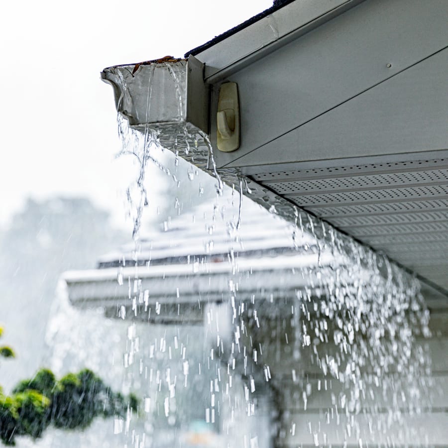 Heavy rainfall falling from gutter on house